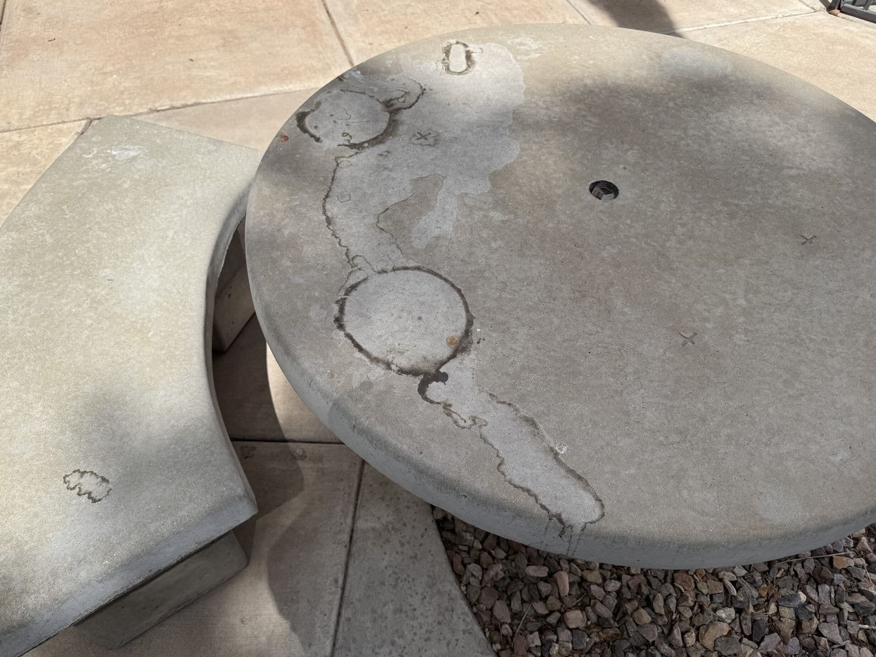 Weathered concrete table with unique circular patterns and markings in an outdoor setting.